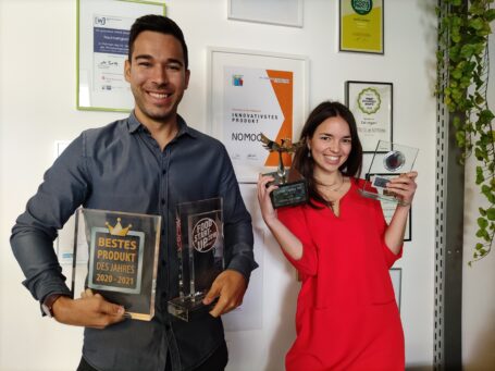Das Bild zeigt Rebecca Göckel und Jan Grabow, Gründer und Geschäftsführer von NOMOO, vor einer Wand mit Auszeichnungen.