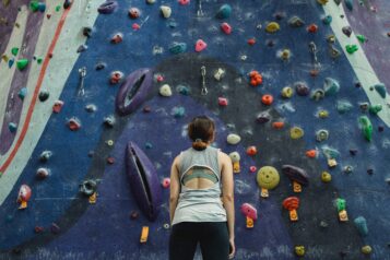 Frau steht vor Kletterwand