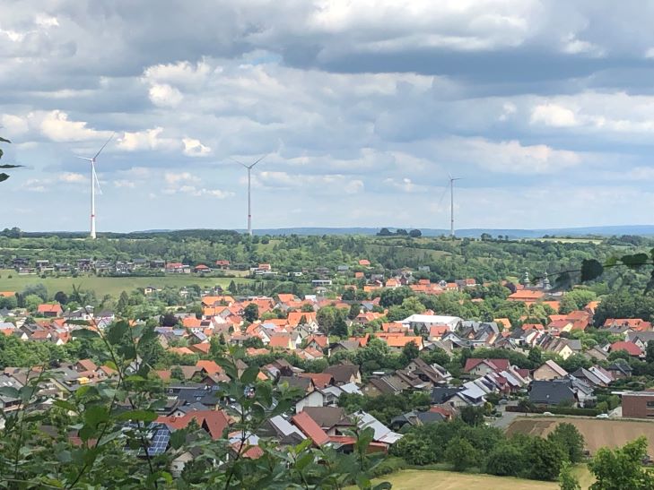 Windpark Willebadessen mit drei Windrädern im Hintergrund, die während des Repowering-Prozesses gebaut wurden mit dem Ort im Vordergrund