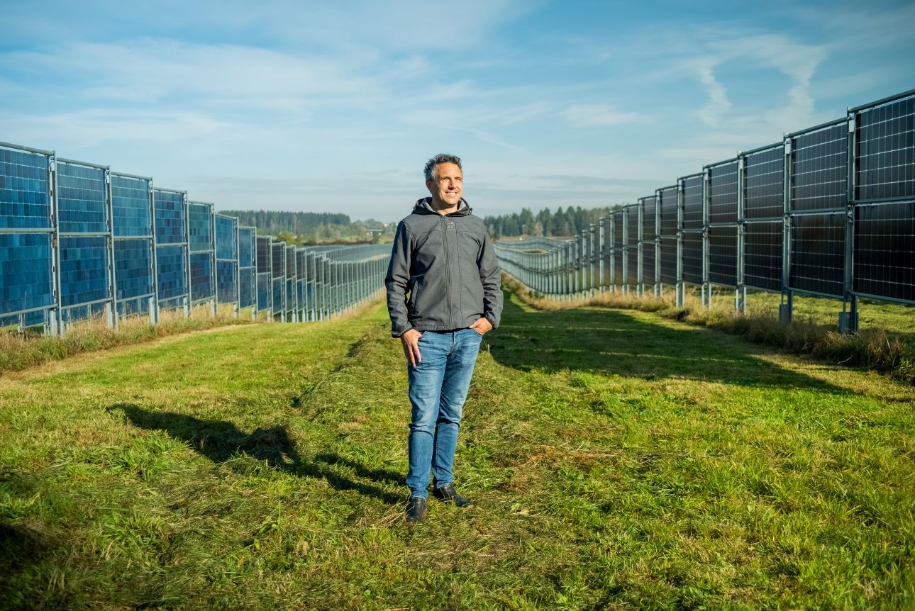 Portrait von Heiko Hildebrandt, Gründer und CEO der Next2Sun-Gruppe, zwischen zwei Solaranlagen-Reihen, er schaut lächelnd in die Ferne